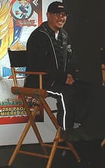 Black and white portrait of Akira Toriyama smiling, with the Will Eisner Comic Awards logo