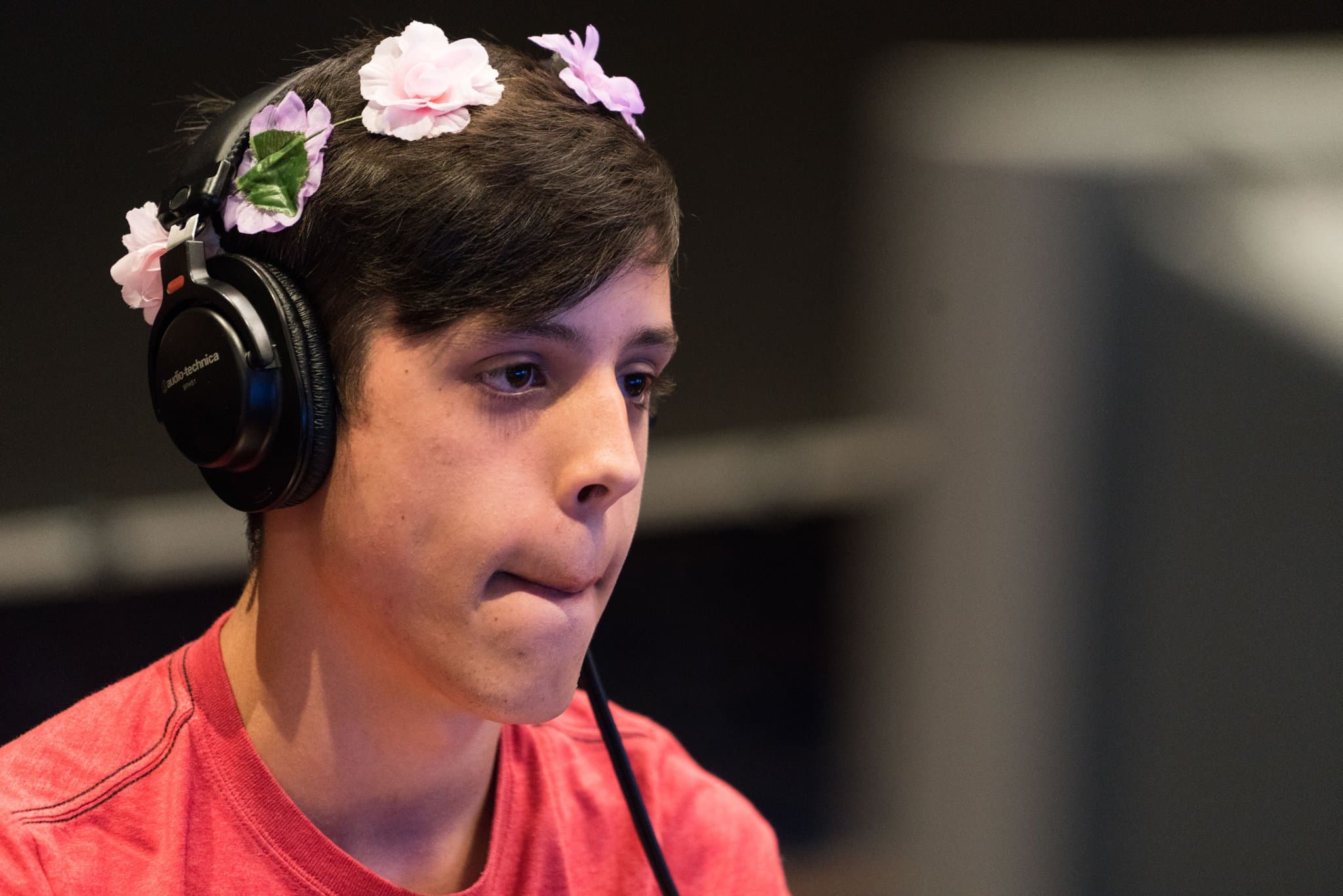 A speedrunner plays a video game on stage at Summer Games Done Quick, with an audience and charity tracker in the background.